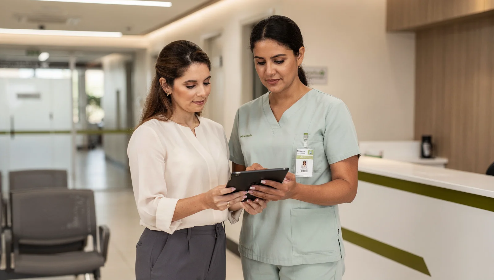 Profissionais conferem um tablet na recepção de uma unidade hospitalar